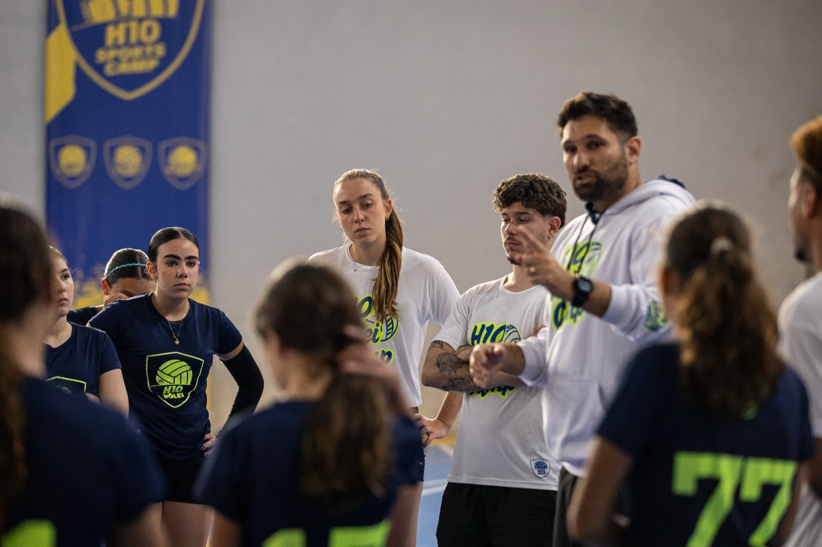 Treinador de moletom H10 orientando a roda de meninas na beira da quadra